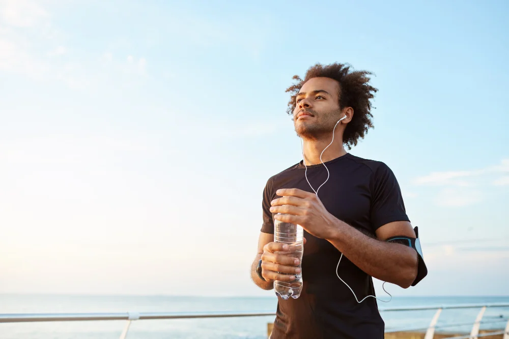 Man athlete drinking water out of plastic bottle after hard running workout