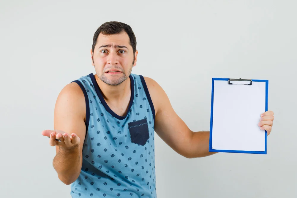 Young man holding clipboard in blue singlet and looking confused
