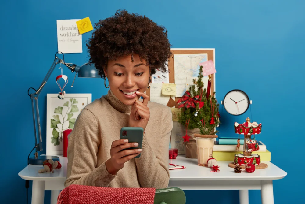 Happy woman using smartphone in a decorated home office.