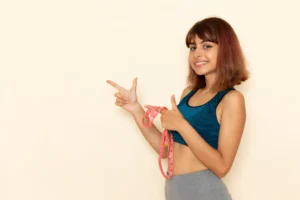 young female with fit body in blue shirt holding waist measure with smile