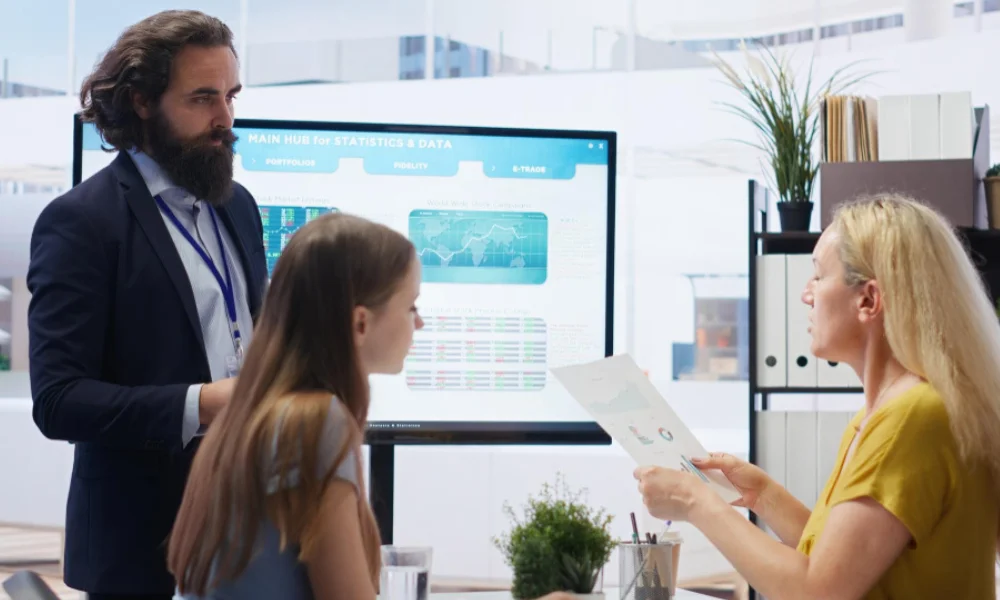 Business team collaborating on a large digital screen with charts and AI insights.