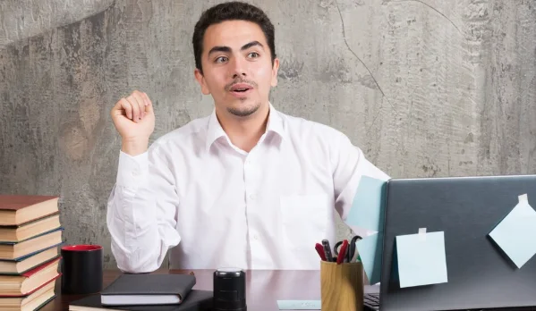 Businessman sitting at the desk with laptop, books and pencils-jhonbaby777