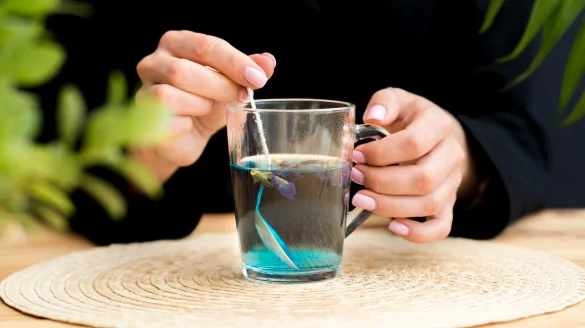 Front view woman stirring blue tea in glass