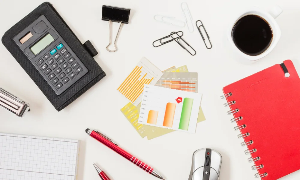 Office desk with calculator, red notebook, coffee cup
