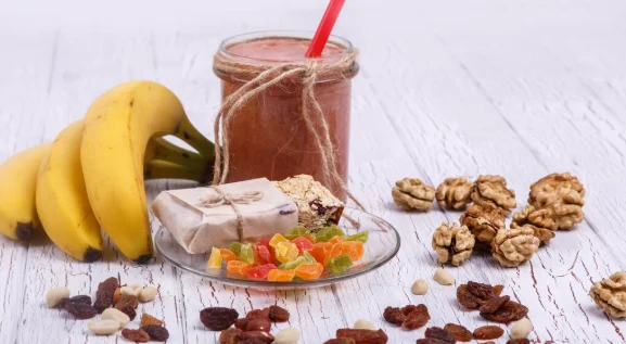 Red detox coctail with bananas, walnut and candied fruits lies on white table