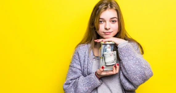 Portrait of a teen brunette girl with cuppingglass money isolated. pot with money in teenage hands-good daily habits