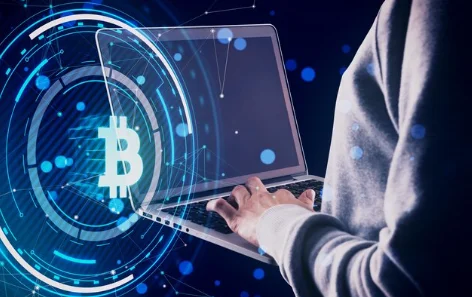 Close up and side view of hands using laptop with glowing round bitcoin hol