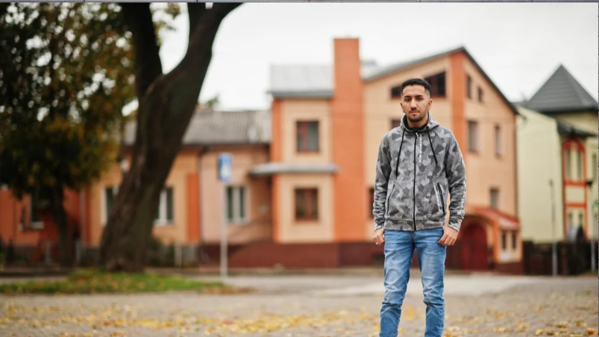 Hipster fashion male in street style with flannel shirt, denim jacket, and vintage sneakers.