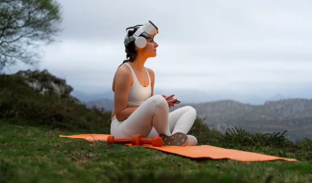 Woman meditating outdoors with a VR headset on a yoga mat-lifestyle and trends