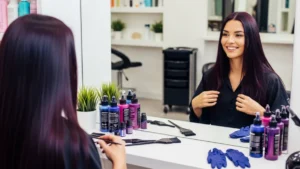 Best hair dye for dark hair woman smiling at salon mirror