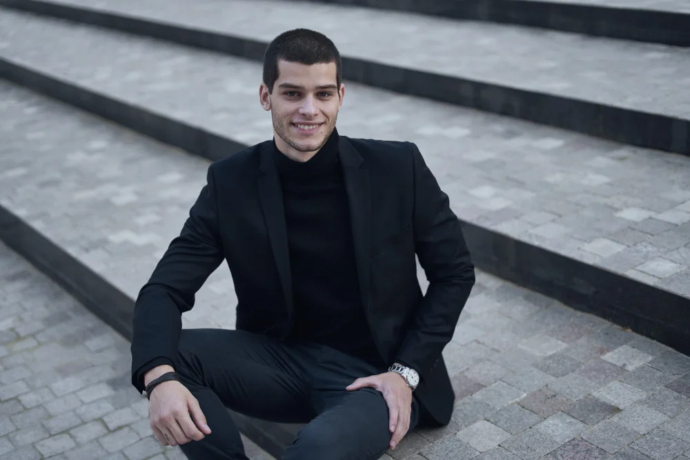 Black monochrome business casual outfit with chinos, dark shirt, and blazer.