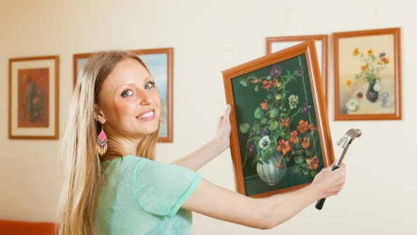 Young woman hanging the art picture-diy for decorating room