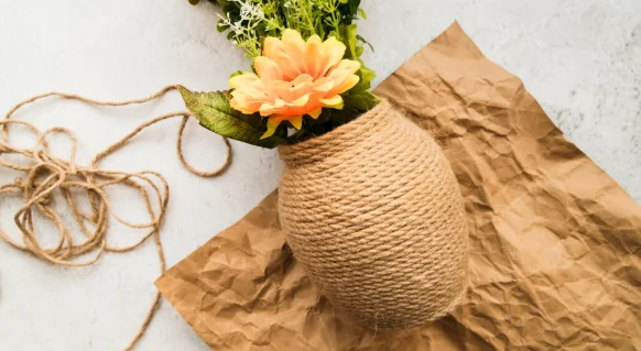 Vase made with string on crumpled brown paper against white backdrop