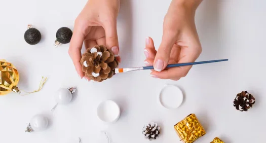 Top view of woman painting pine cone--diy crafts for home decor