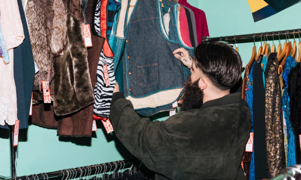 Man looking at wardrobe with variety of different clothing styles.