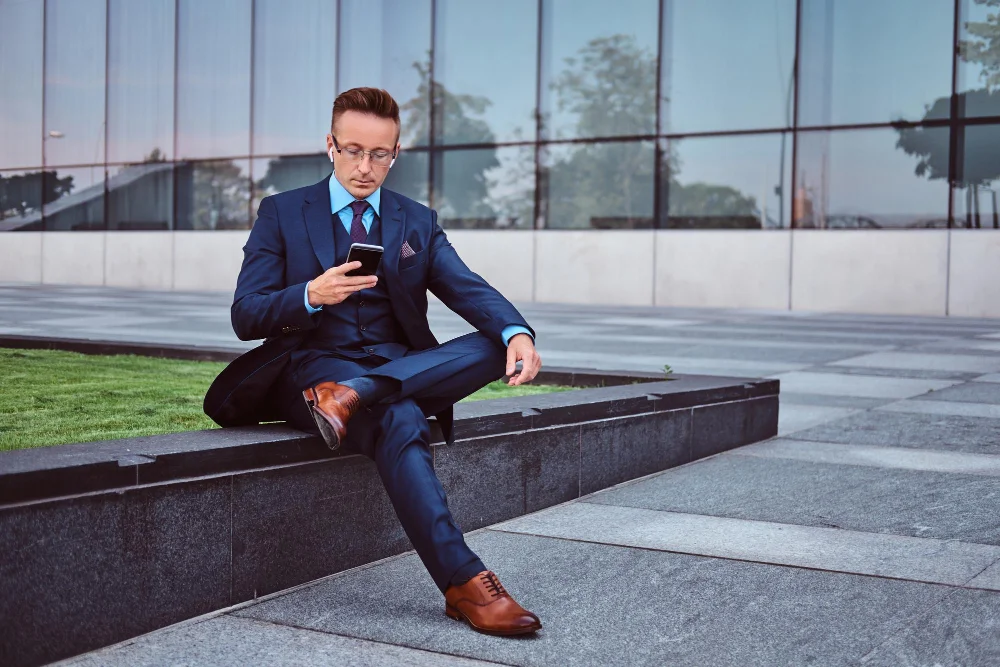 Man wearing a tailored navy suit with polished leather shoes.
