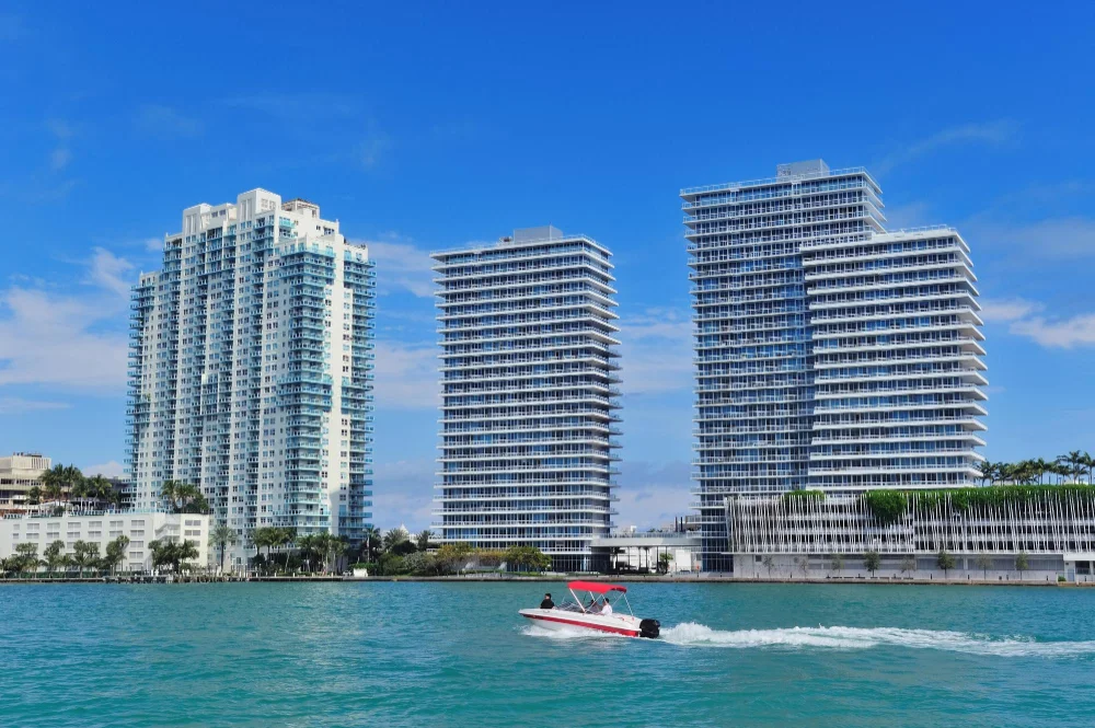 Modern waterfront condos in Miami with a speedboat passing by