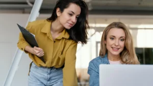 Two women in business casual looks for women working together at a laptop.