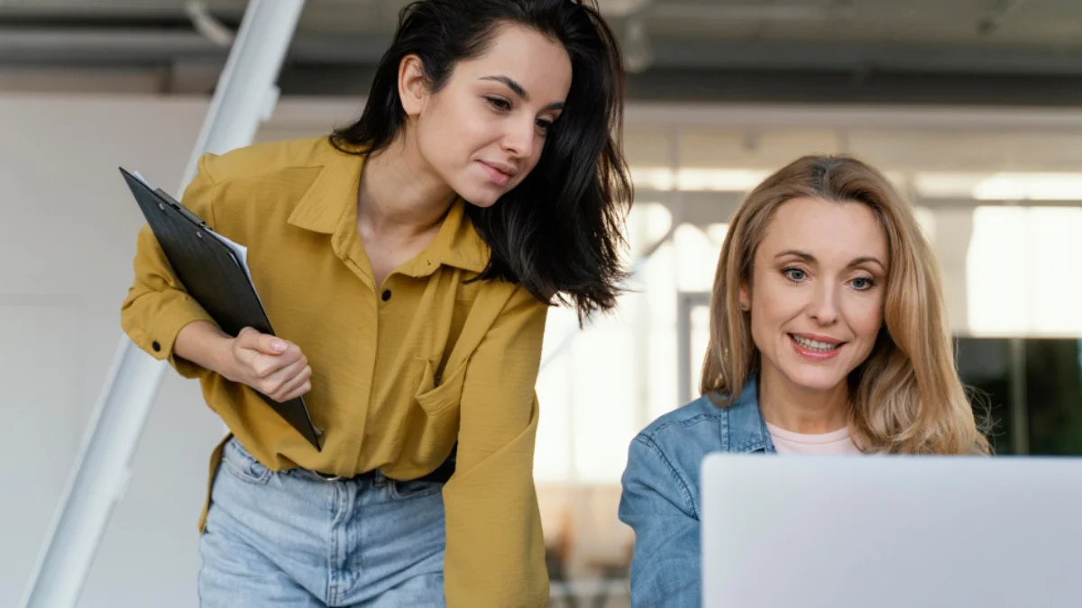 Two women in business casual looks for women working together at a laptop.