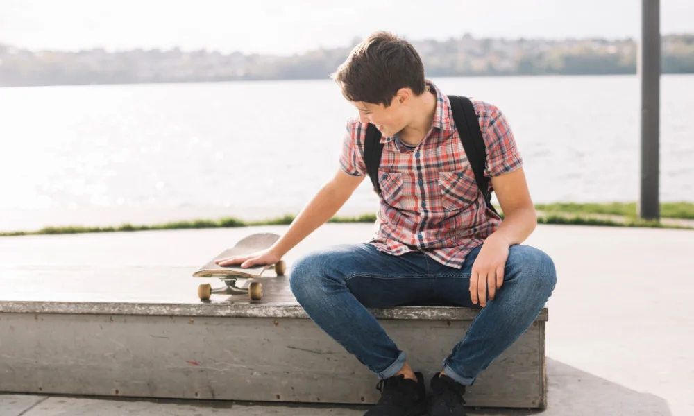 Young man in flannel shirt, skinny jeans, and retro sneakers posing outdoors.